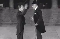 Two men in top hats salute each other