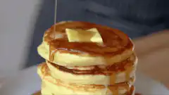 Syrup poured on pancakes with butter
