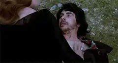Man lying on grass with woman touching his chest