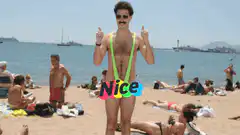 Man in neon green speedo giving thumbs up on beach