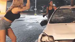 Two women smashing a car with bats