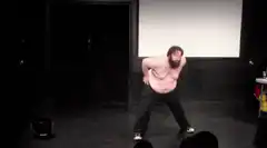 Bearded man dancing shirtless on stage