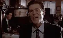 Willem Dafoe raises hand and smirks