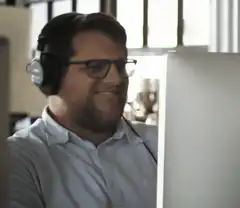 Man with headphones smiling at computer