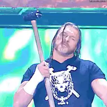 AJ Styles holding a sledgehammer and pointing