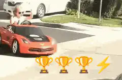 Toddler in toy car with trophies