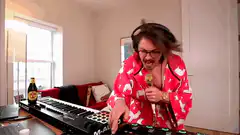 Man in red robe singing into golden mic