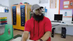 Man in red hoodie laughs and clutches chest