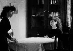Woman standing over seated woman at table