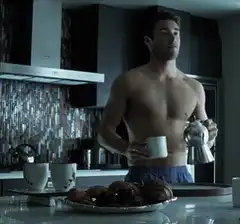 Shirtless man pouring coffee in kitchen