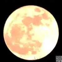 Silhouette of cyclist riding past giant moon