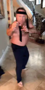 Shirtless man in suspenders doing karate