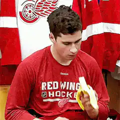 Man in red shirt eating banana