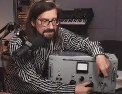 Man in striped shirt turns knob on device