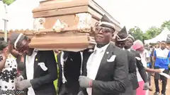 Men dancing while carrying a coffin