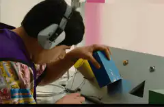 Boy with headphones tries to fit a blue block