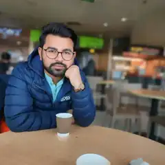 Man in blue jacket resting chin on hand