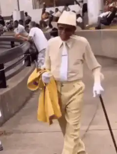 Old man in yellow suit dancing with cane
