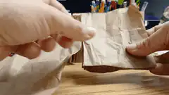 Hands folding brown paper into a stack