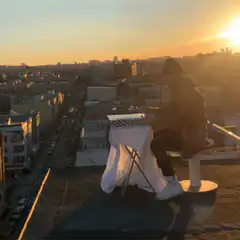 Person eating pizza on rooftop at sunset