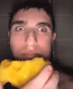 Man eating yellow bell pepper in shower