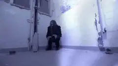 Long-haired man stands up in a blue room