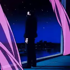Man in black suit looking out window at night