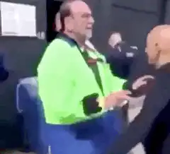 Man in green jacket arguing with bald man
