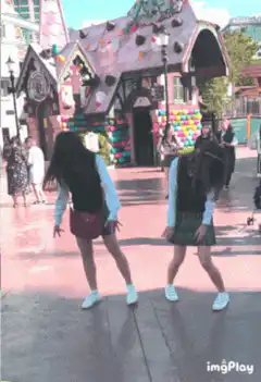 Two girls dancing in front of a candy house