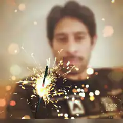 Man holding a sparkler with bokeh lights