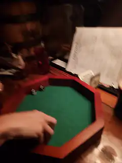 person rolling dice in octagonal tray