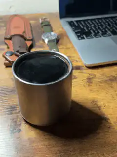 steaming metal cup on wooden desk