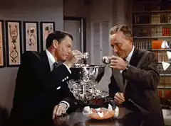 Two men drinking from a silver bowl