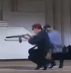 Two men shooting guns back to back