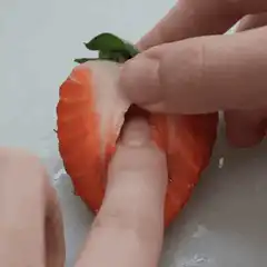 Fingers splitting a hollow strawberry