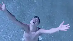 Man standing in heavy rain with arms outstretched