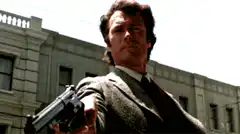 Clint Eastwood smiles after pointing gun