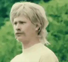 Man with mullet and mustache looking confused