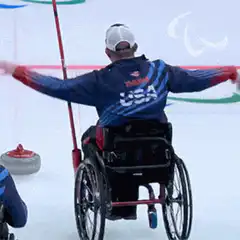Wheelchair curler celebrates with arms raised