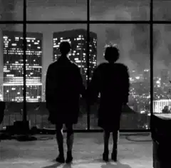 Silhouettes holding hands looking at city