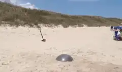 Man jumps over metal dome on beach