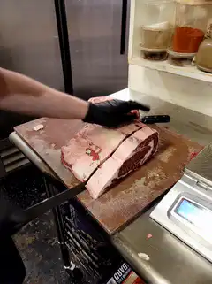 Chef slicing large raw meat on cutting board