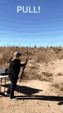 Woman pulls shotgun trigger in desert