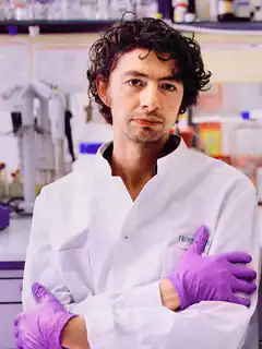 chemist in lab coat with purple gloves