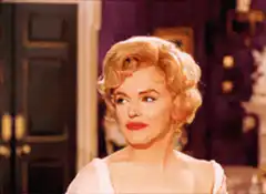 Marilyn Monroe laughing and covering her mouth