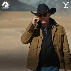 Man in cowboy hat removes sunglasses