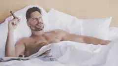 Shirtless man in bed smoking a cigar