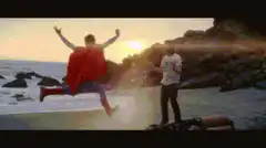 Man in cape flies into another man on beach