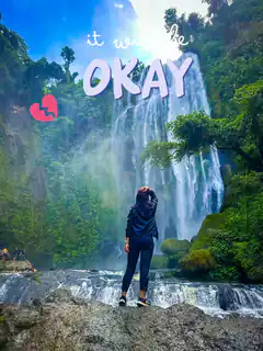 woman standing by waterfall with it will be okay text