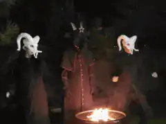 Three masked figures dancing around a fire